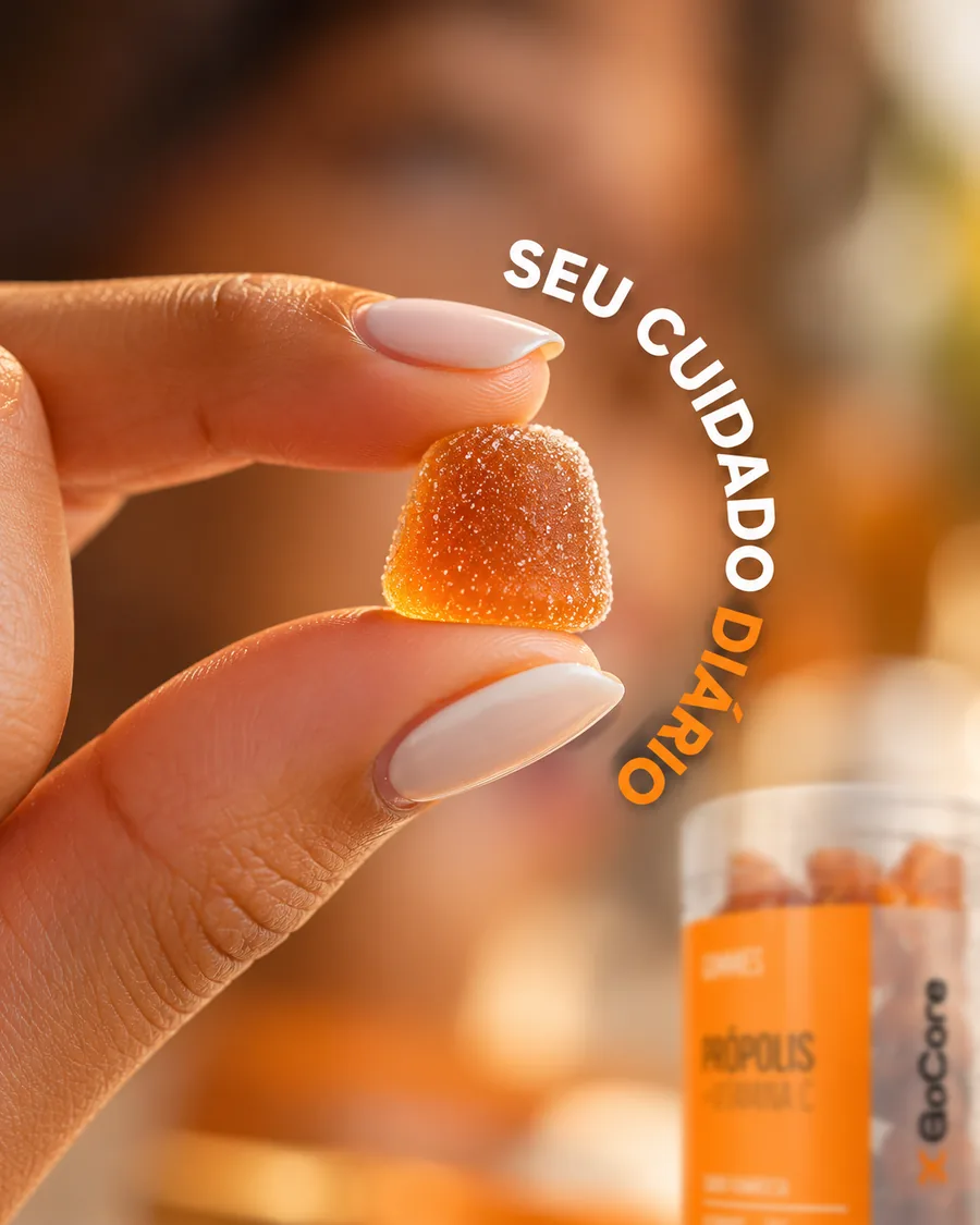 Goma de própolis entre os dedos, com o pote GoCore ao fundo